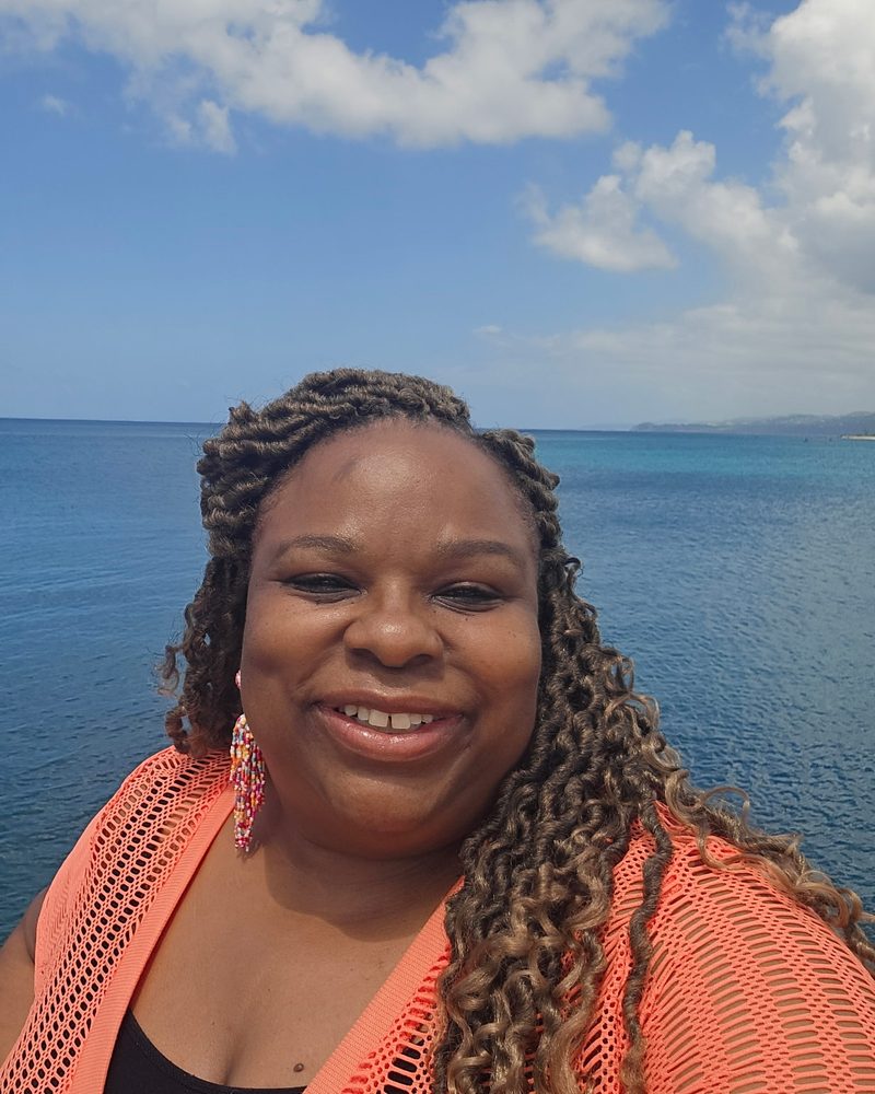 Andrea Royster smiling on a sunny day by the ocean